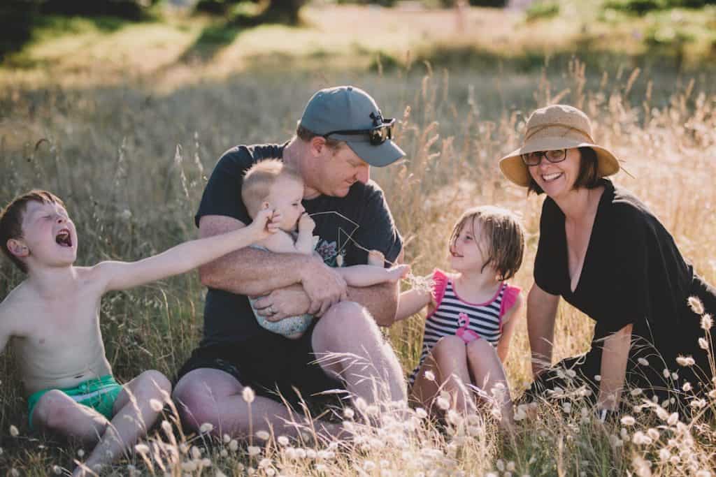 A family with 2 parents and 3 children sitting amongst rabbit tail grass