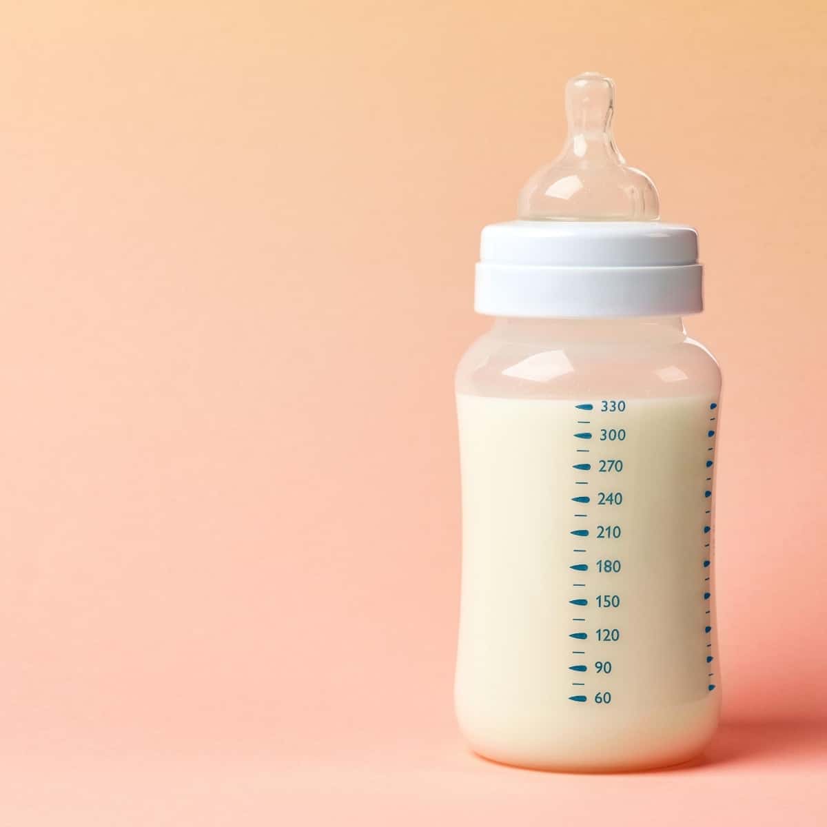 full bottle of baby formula on an apricot background