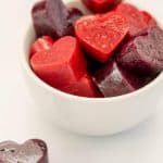 red and purple heart shaped gummies in a white bowl with text overlay
