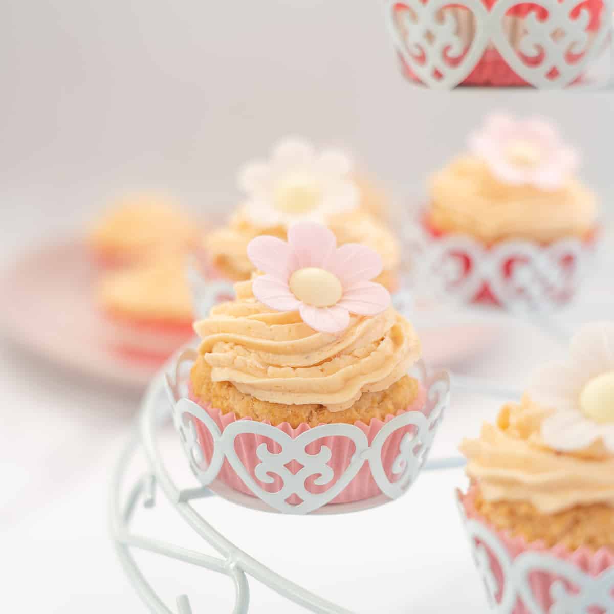 dairy free cupcakes frosted with pink icing and a flower in a white cupcake holder
