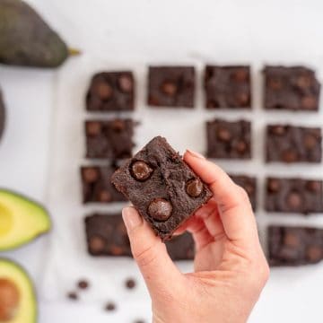 women's hand holding a piece of avocado brownie