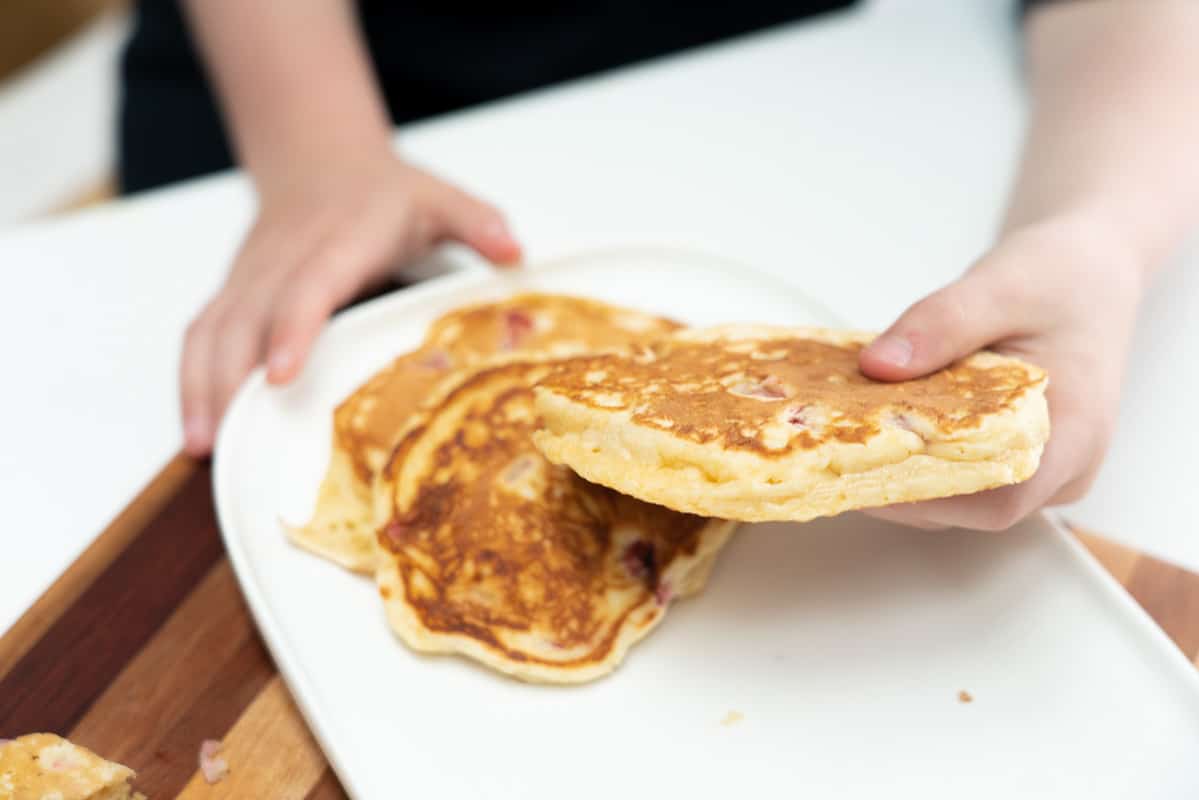 Child's hand holding a fluffy pancake