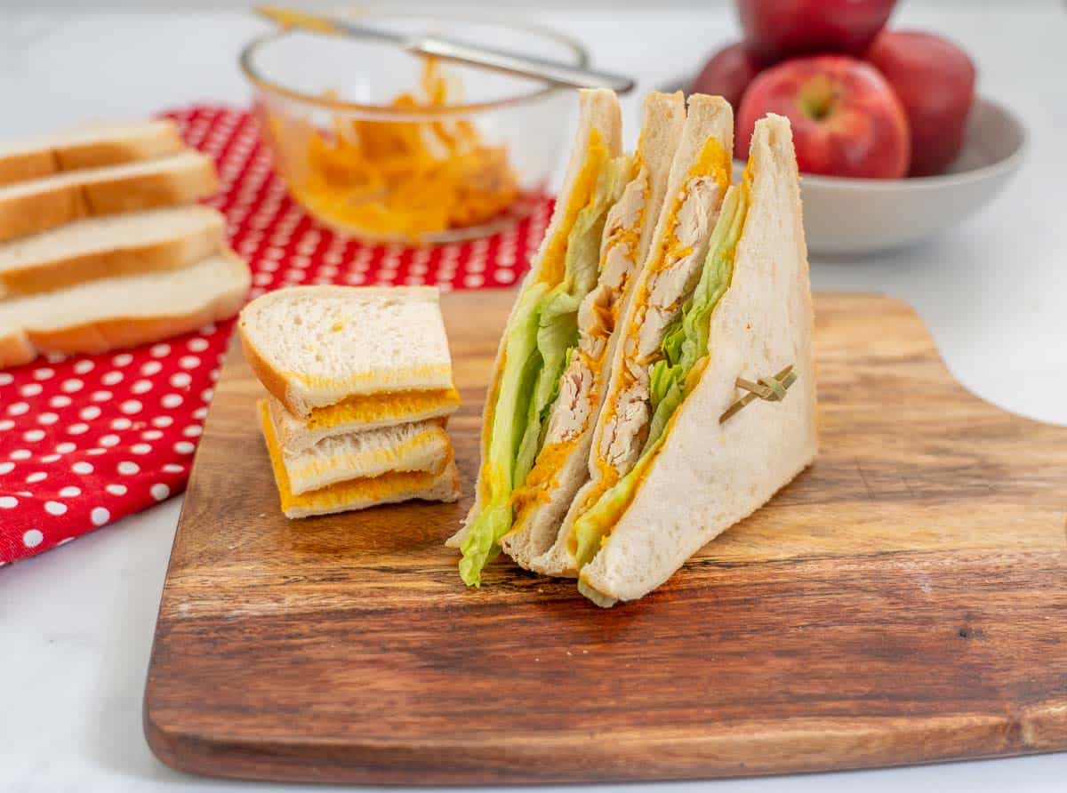 sandwiches on a wooden chopping board with a bowl of roast vegetable spread in the background