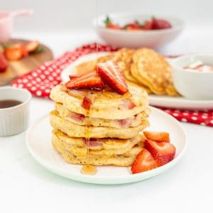 Stack of strawberry pancakes drizzled with maple syrup