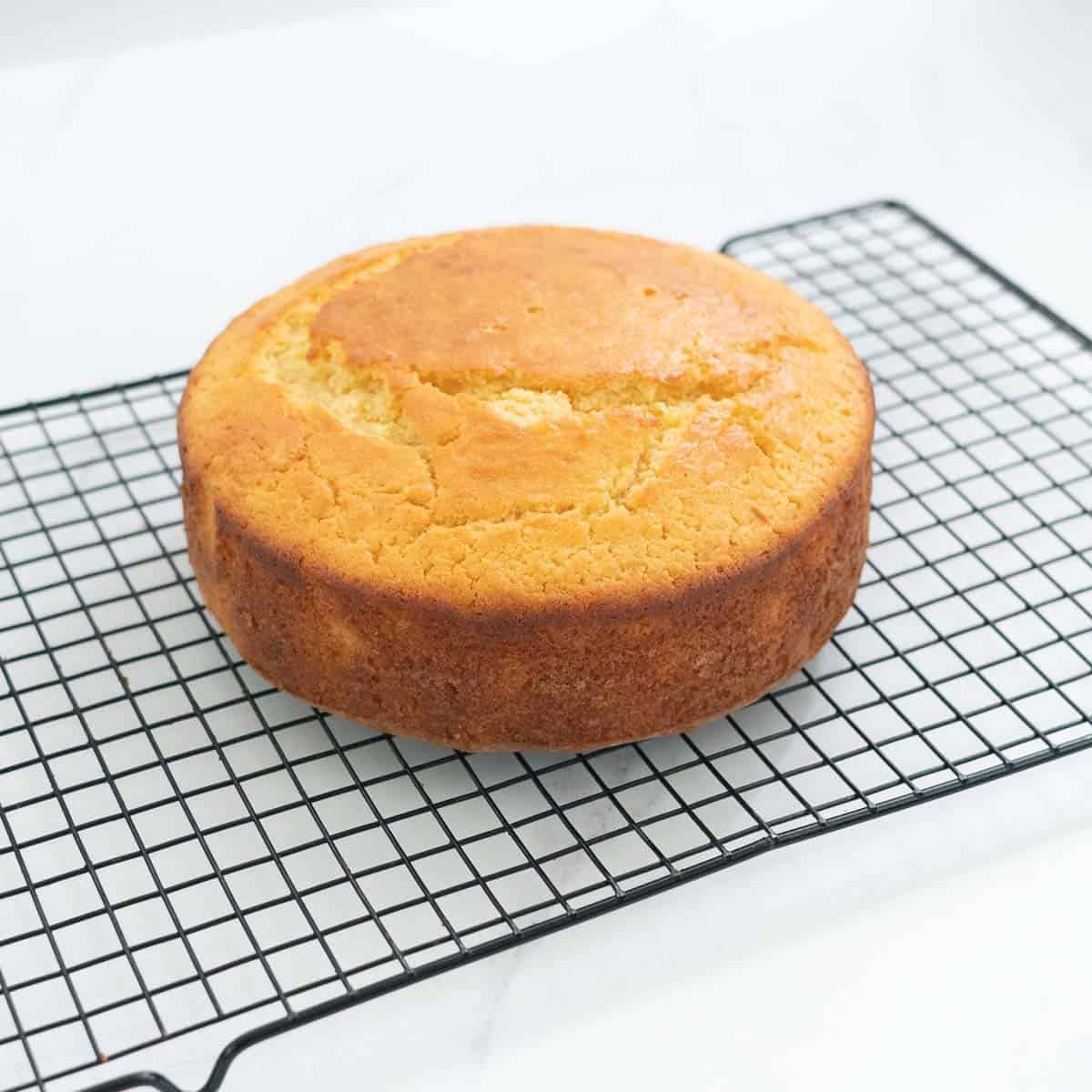 a round cake with a golden colour sitting on a wire rack to cool