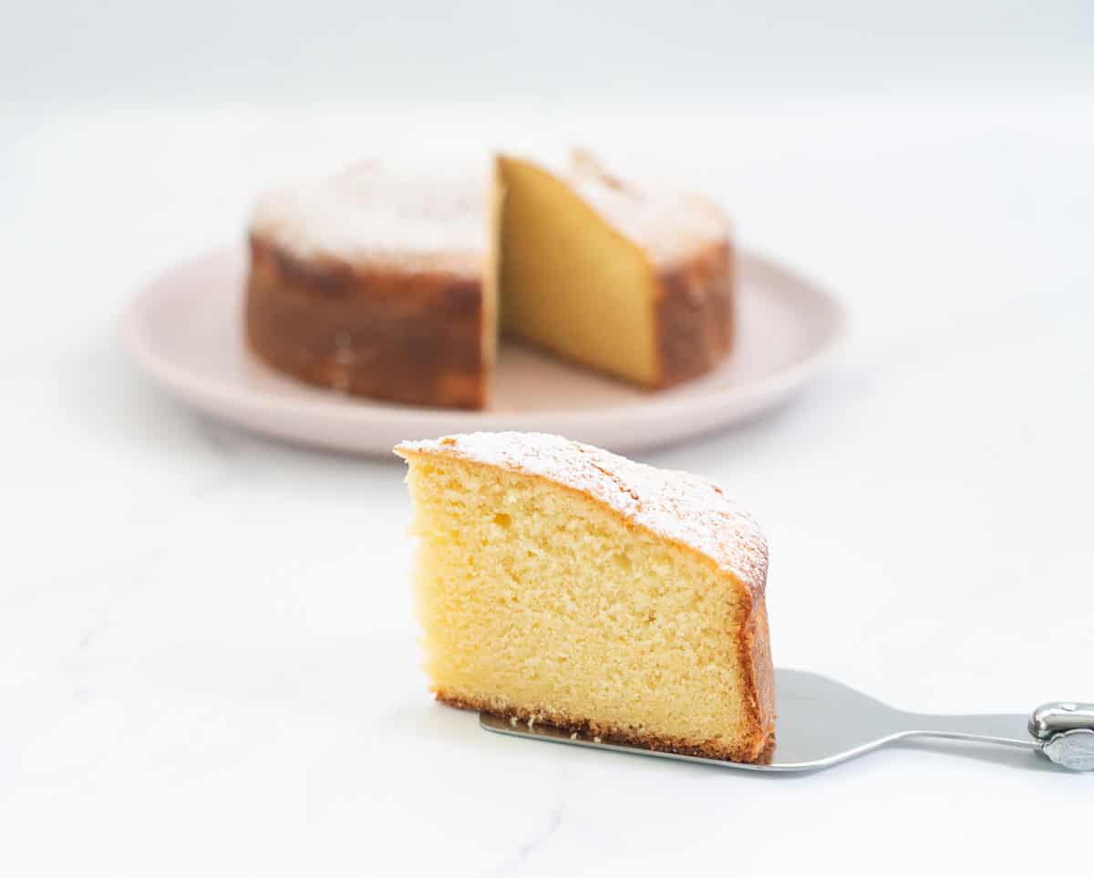 A slice of vanilla cake sitting on a marble bench top