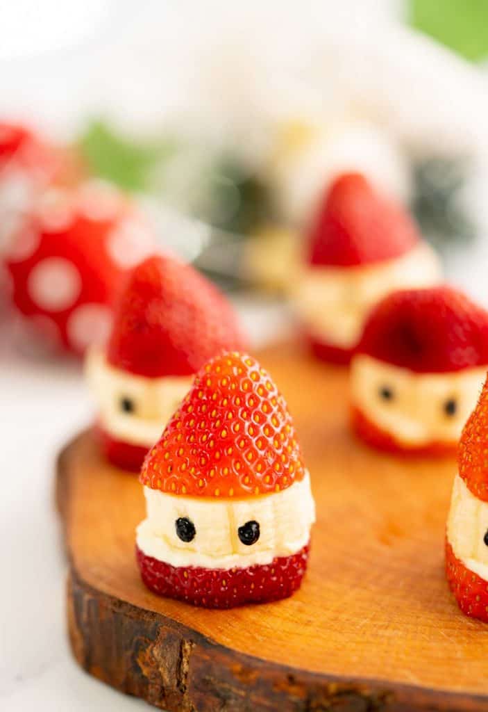 Strawberry Santas sitting on a wooden board.