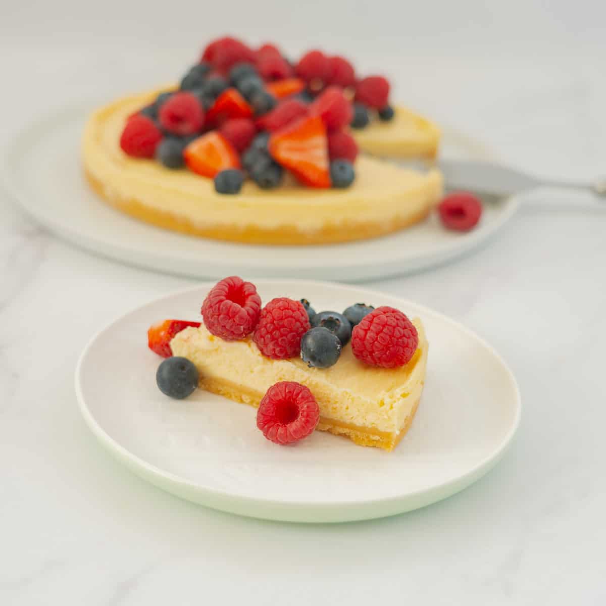 A slice of cheesecake topped with berries sitting on a white plate.