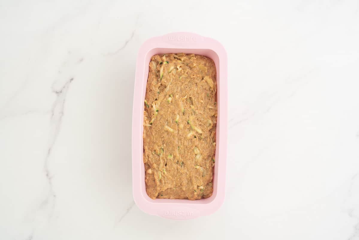 zucchini banana bread batter in a pink silicone loaf tin ready for baking