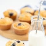 A blueberry muffin sitting next to a glass of milk with a straw, text overlay 'simple blueberry muffins'.