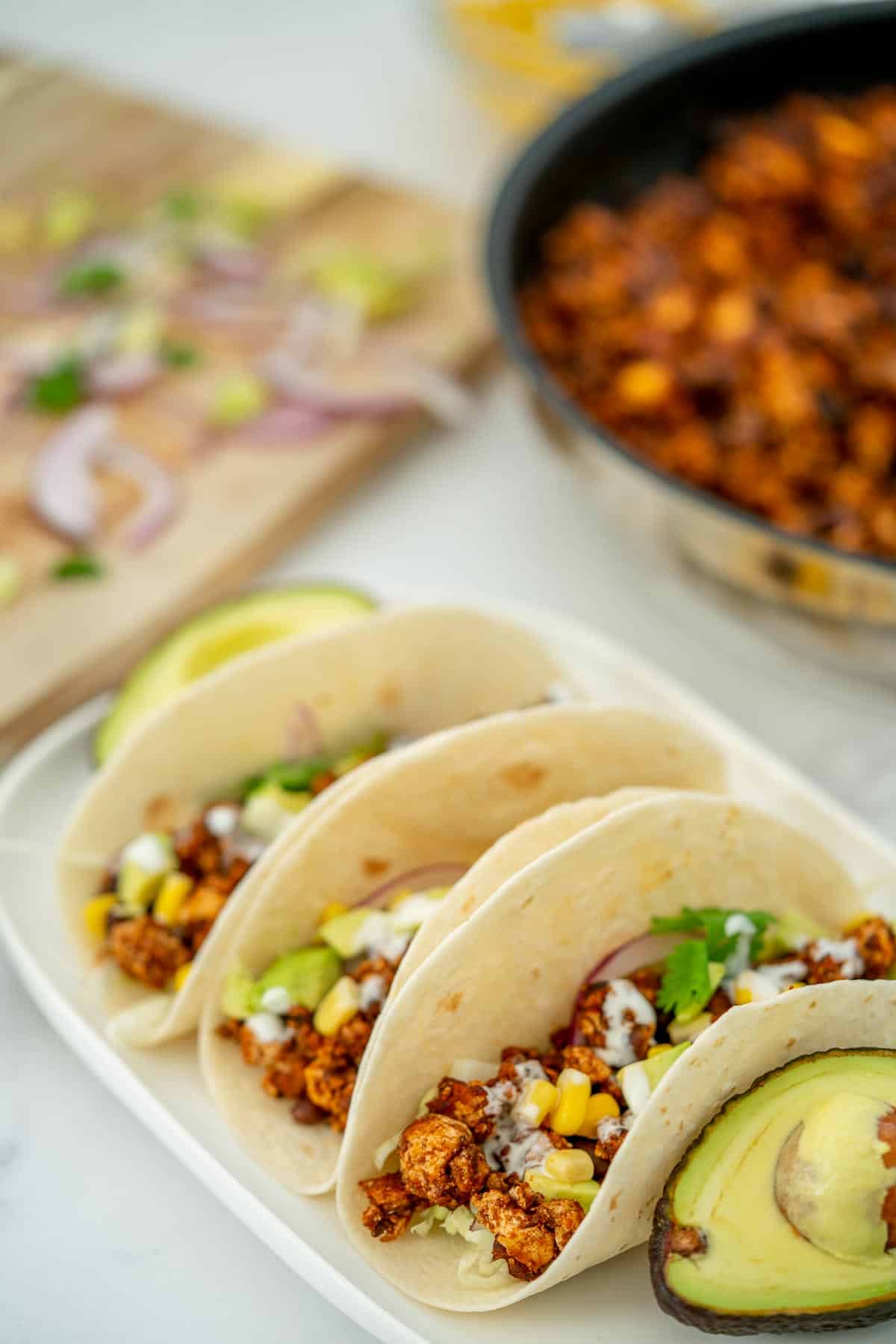3 soft tacos filled with Mexican tofu crumbles on a white platter.