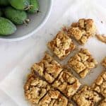 Feijoa crumble slice on baking paper next to a bowl of feijoas.