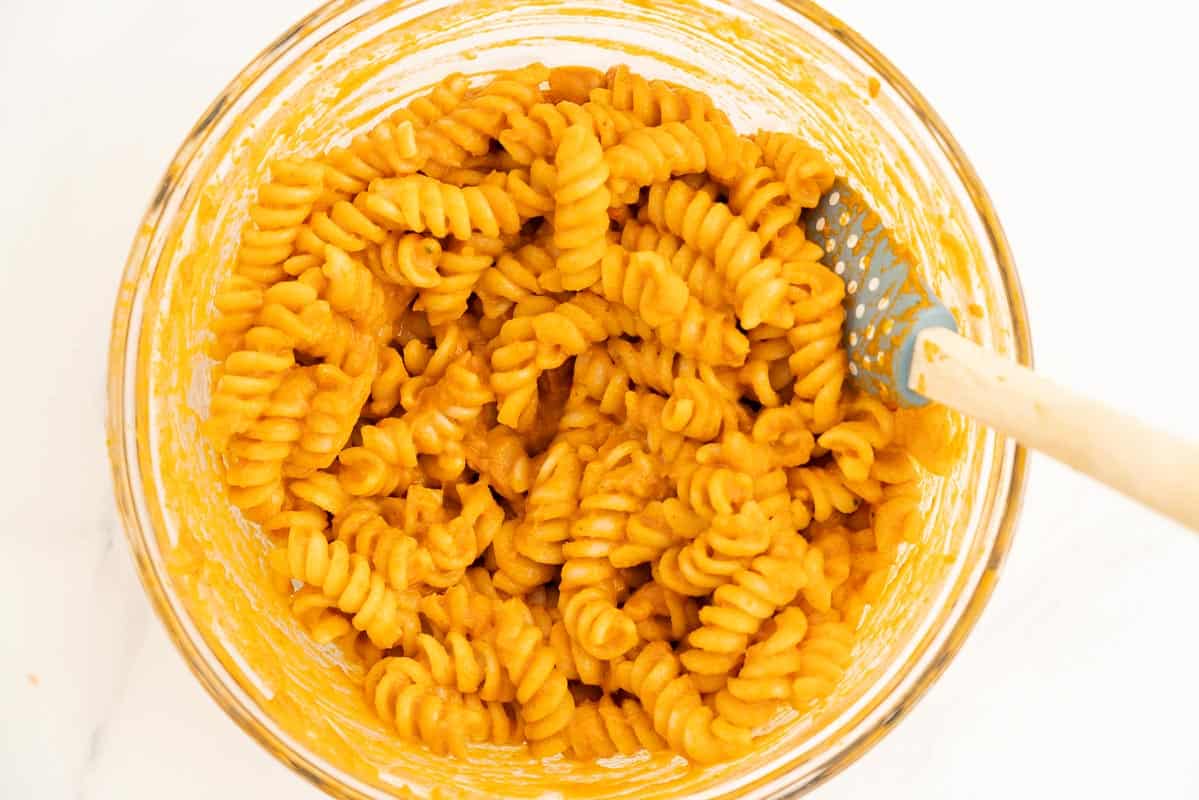 Sauce covered pasta spirals in a large glass mixing bowl.