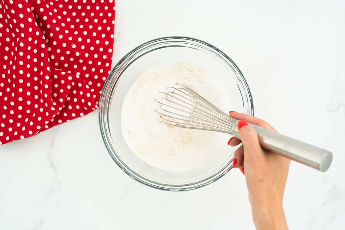 Flour and sugar in a large glass bowl being whisked