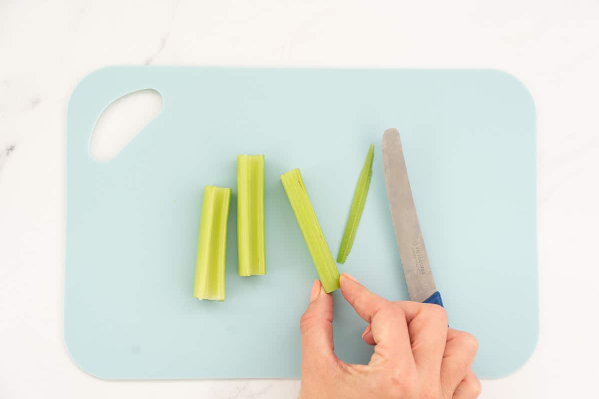 Celery sticks on a light blue chopping board.