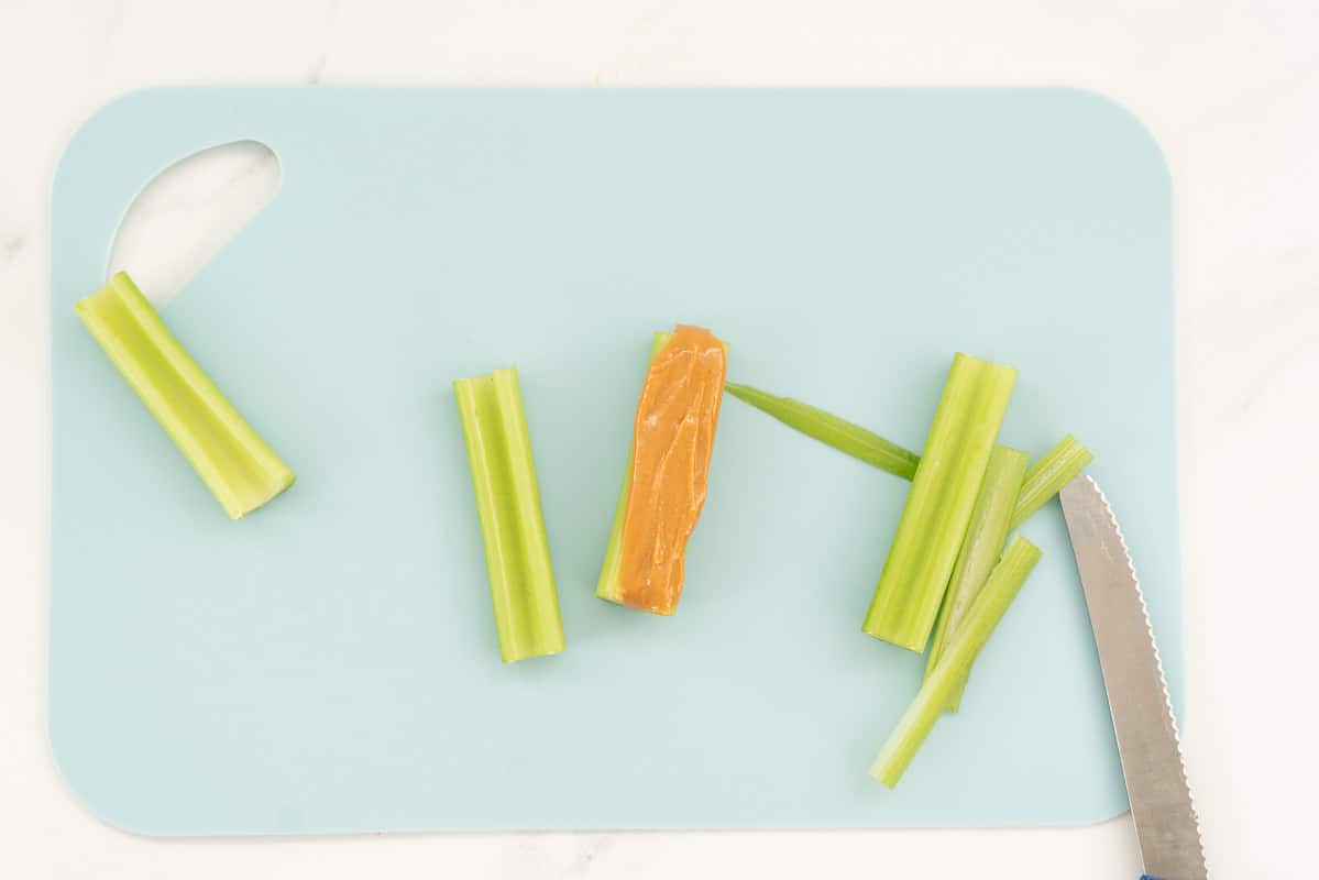 Celery sticks on a blue chopping board, one filled with peanut butter