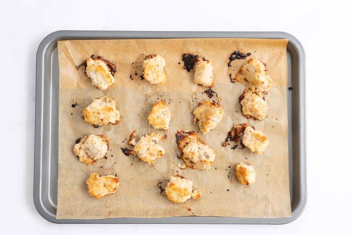 Baked gluten free chicken nuggets on a baking paper lined oven tray.