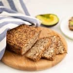 Seeded oat bread sliced on a wooden chopping board.