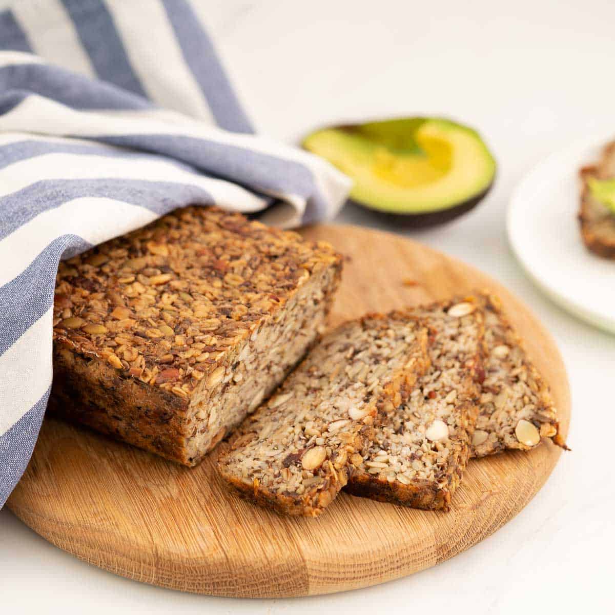 Seeded oat  bread sliced on a wooden chopping board.