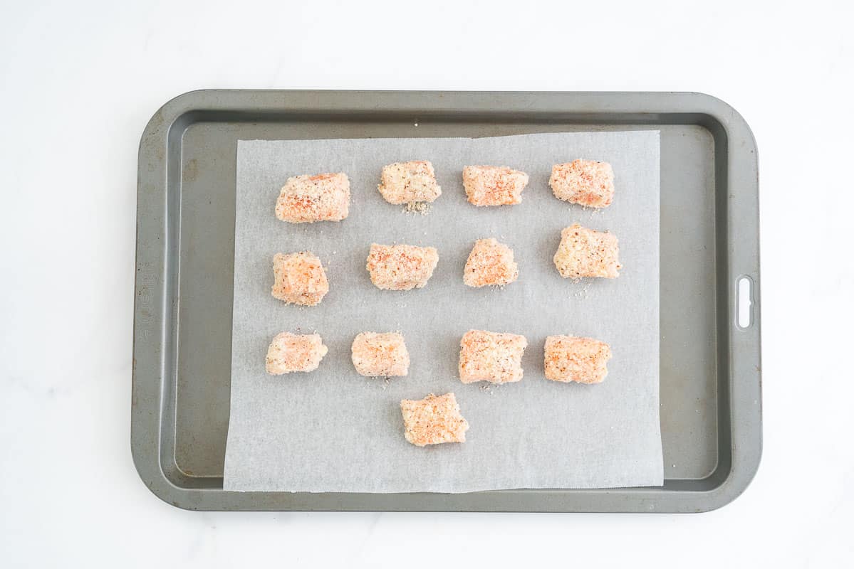 Almond crumbed pieces of salmon on a baking paper lined oven tray.