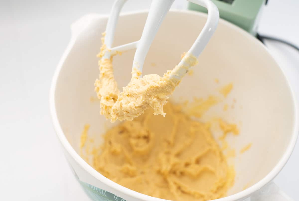 Creamed butter sugar and condensed milk in the mixing bowl of a stand mixer.