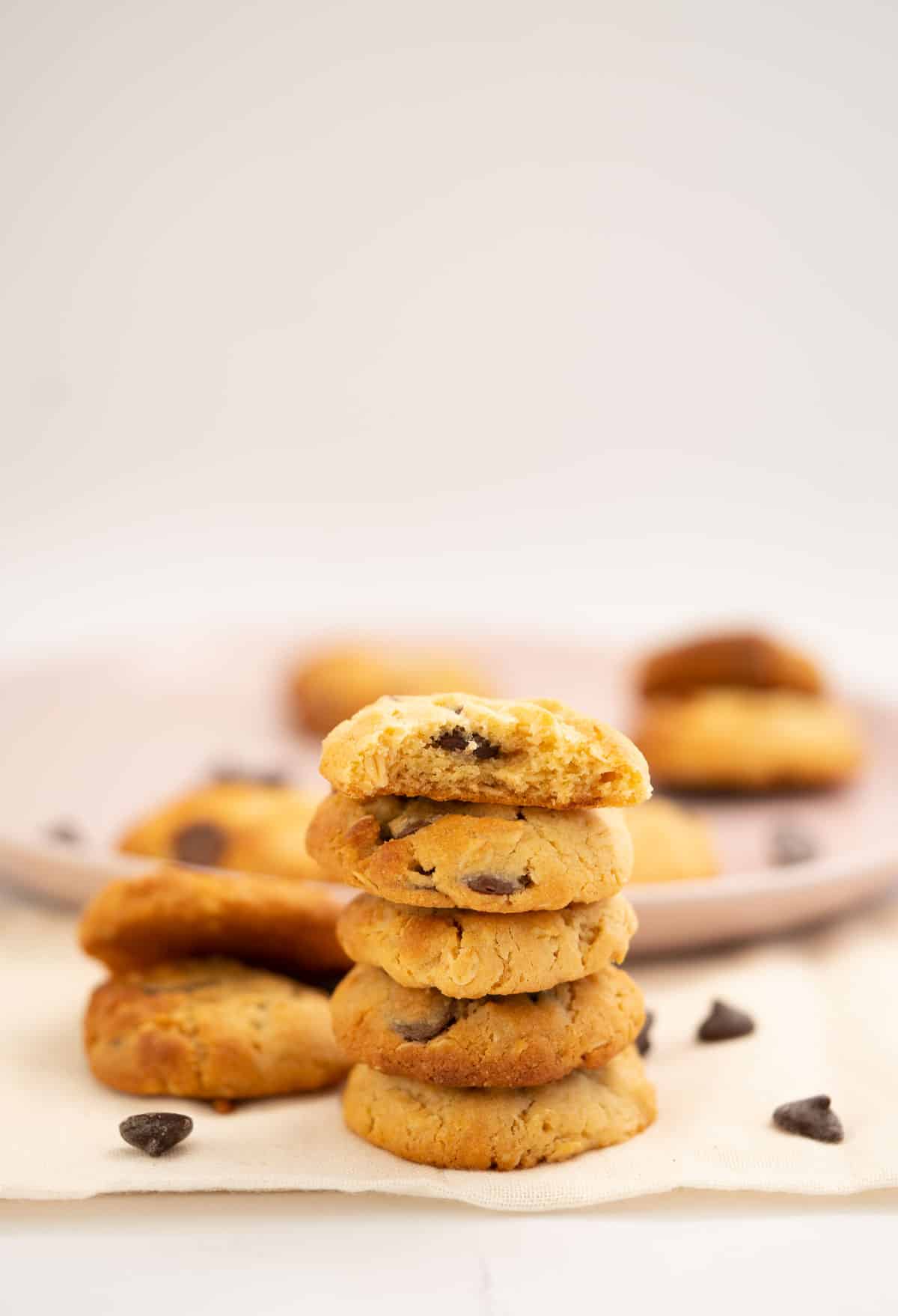 A stack of 5 condensed milk cookies in front of a plat of more cookies.
