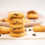 A stack of 5 condensed milk cookies in front of a plat of more cookies.