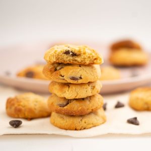 A stack of 5 condensed milk cookies in front of a plat of more cookies.