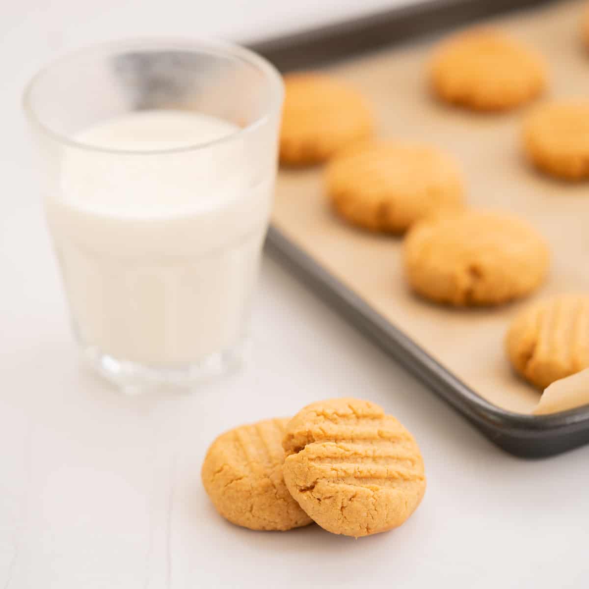 Two cookies next to a glass of milk.