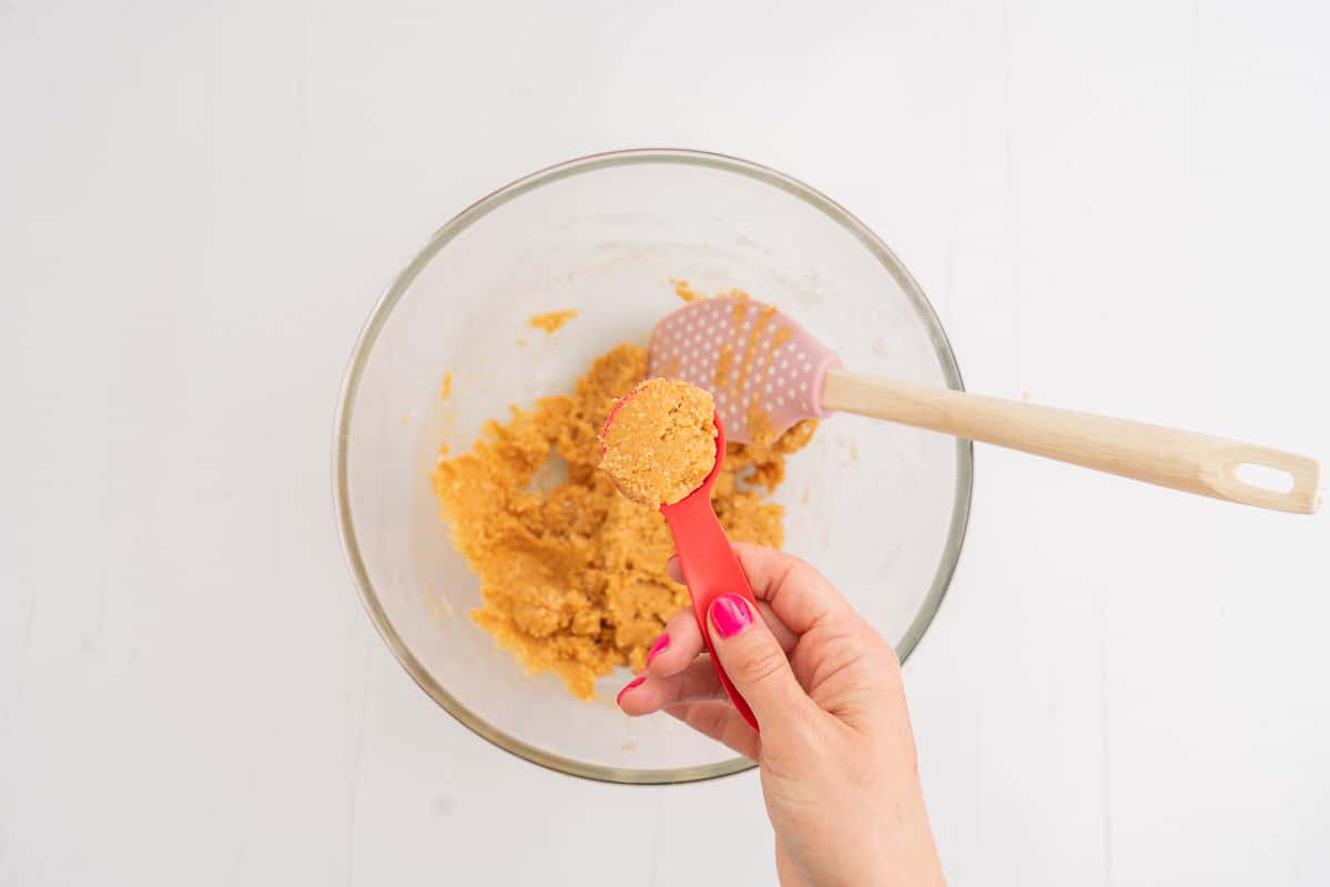 Peanut butter cookie dough scooped in a red measuring spoon.