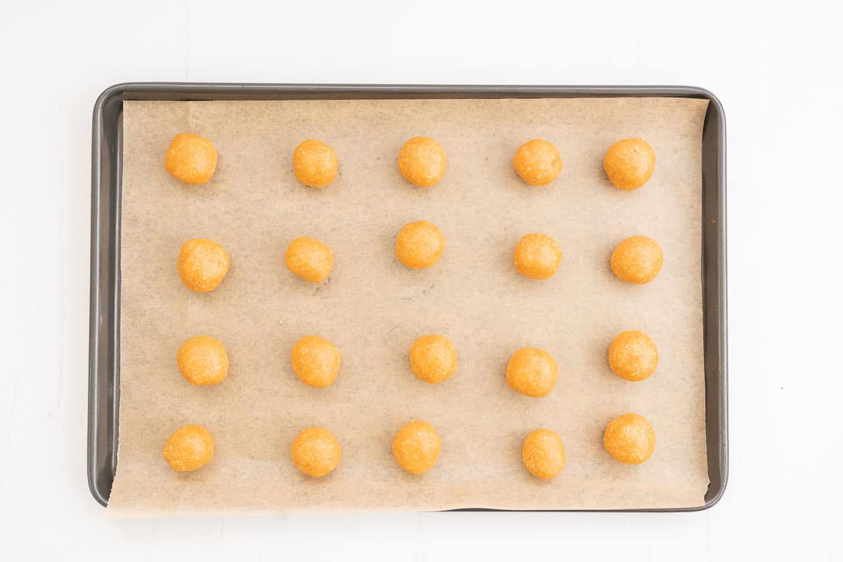 Balls of cookie dough on a baking paper lined tray.