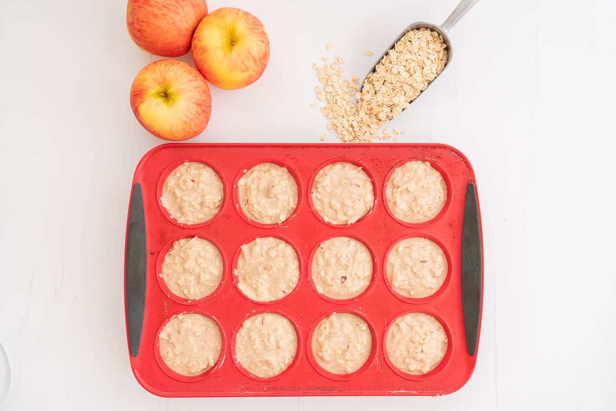 Healthy apple muffin batter portioned into a red silicone 12 cup muffin pan