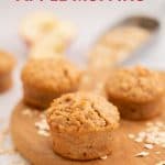 Apple muffins on a wooden chopping board scattered with rolled oats, with text overlay.