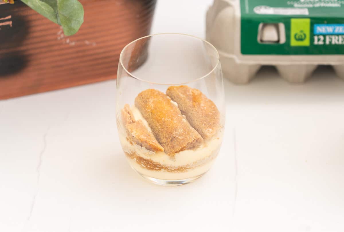 Layers of mascarpone cream and coffee soaked savoiardi biscuits in a glass.