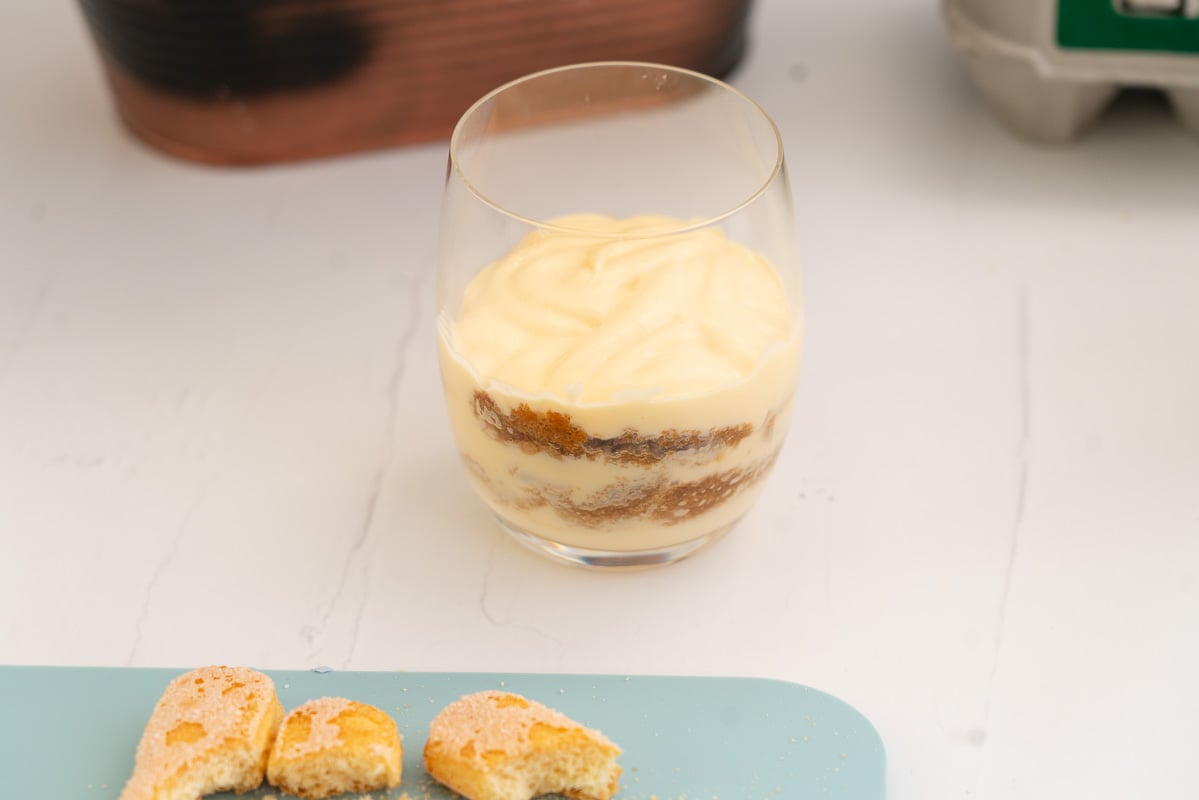 Layers of mascarpone cream and coffee soaked savoiardi biscuits in a glass.