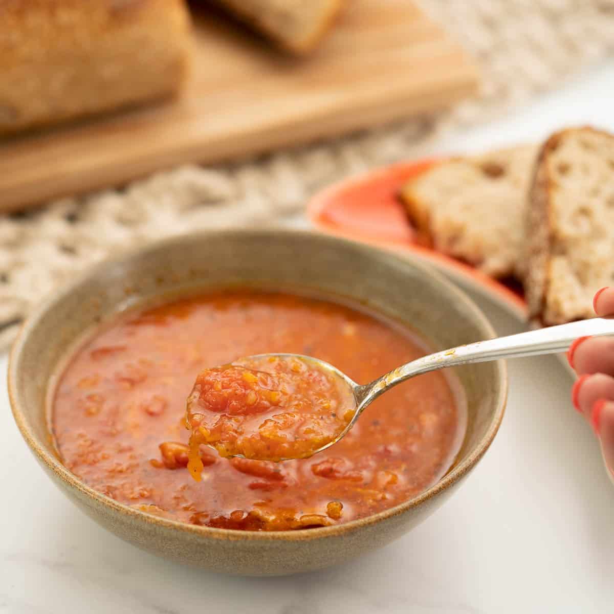 A brown ceramic bowl of tomato soup.