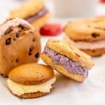 3 diffferent flavoured ice cream cookie sandwiches with frozen fruit pieces.