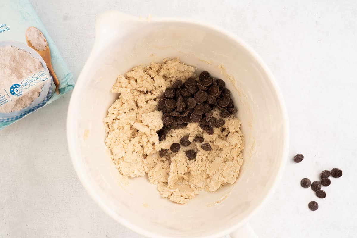 Cookie dough in a white mixing jug with chocolate drops.