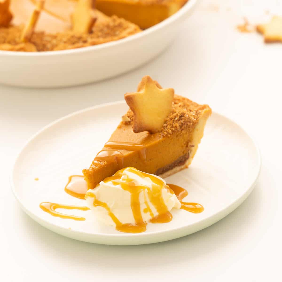 A slice of sweet potato pie decorated with a pastry star, whipped cream and caramel sauce.
