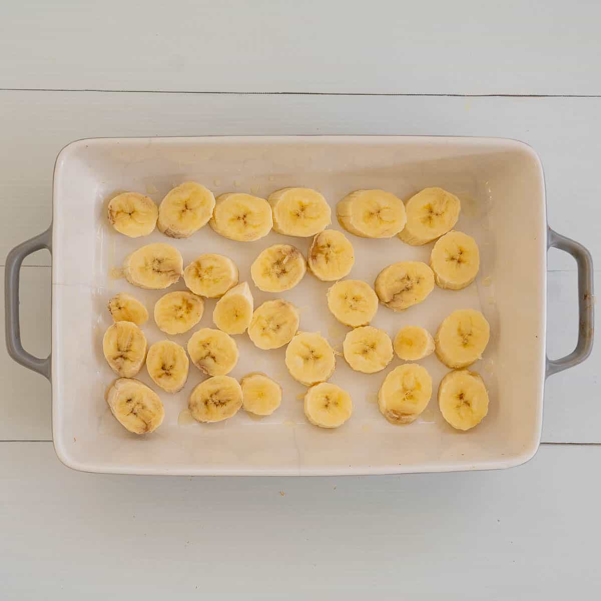 Banana slices covering the bottom of a rectangular baking dish.