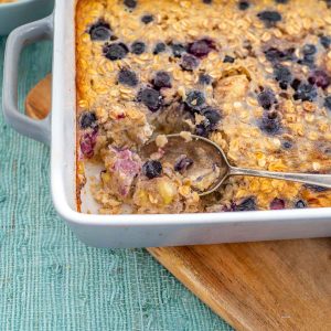 Baked oats topped with blueberries in a grey ceramic baking dish.