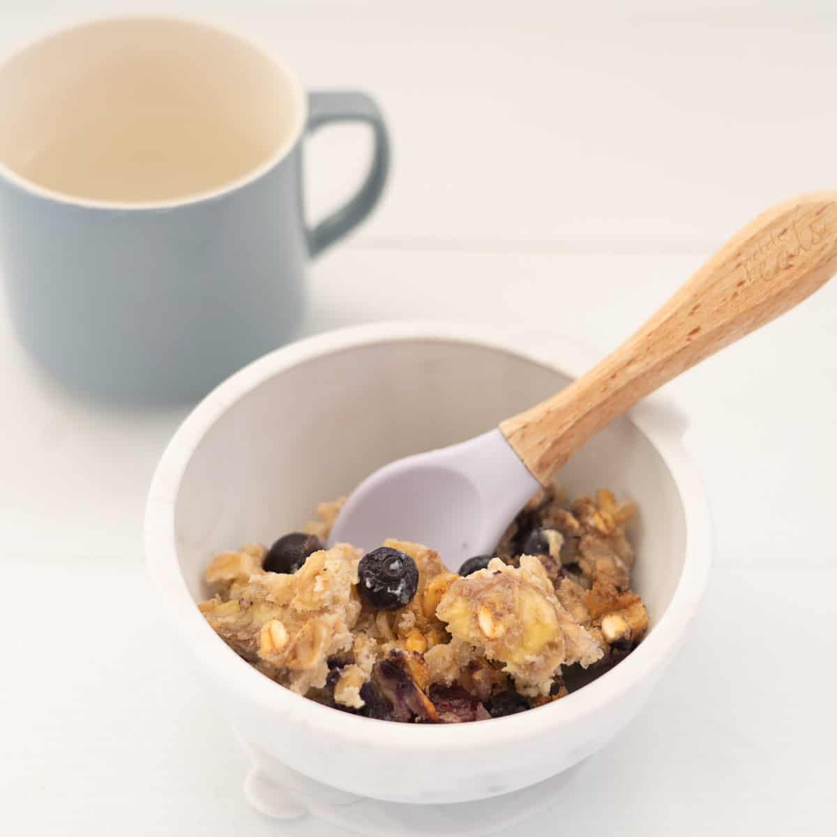 A baby bowl with a silicone spoon filled up with blueberry baked oats.