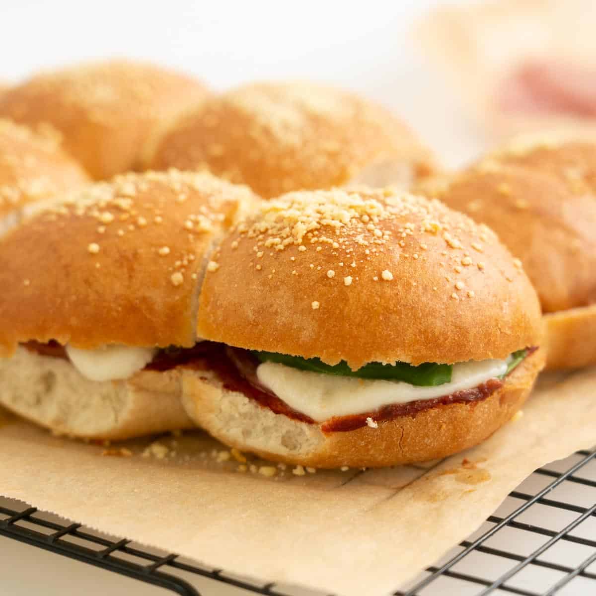 Toasted sliders filled with salami melted mozzarella and spinach leaves.
