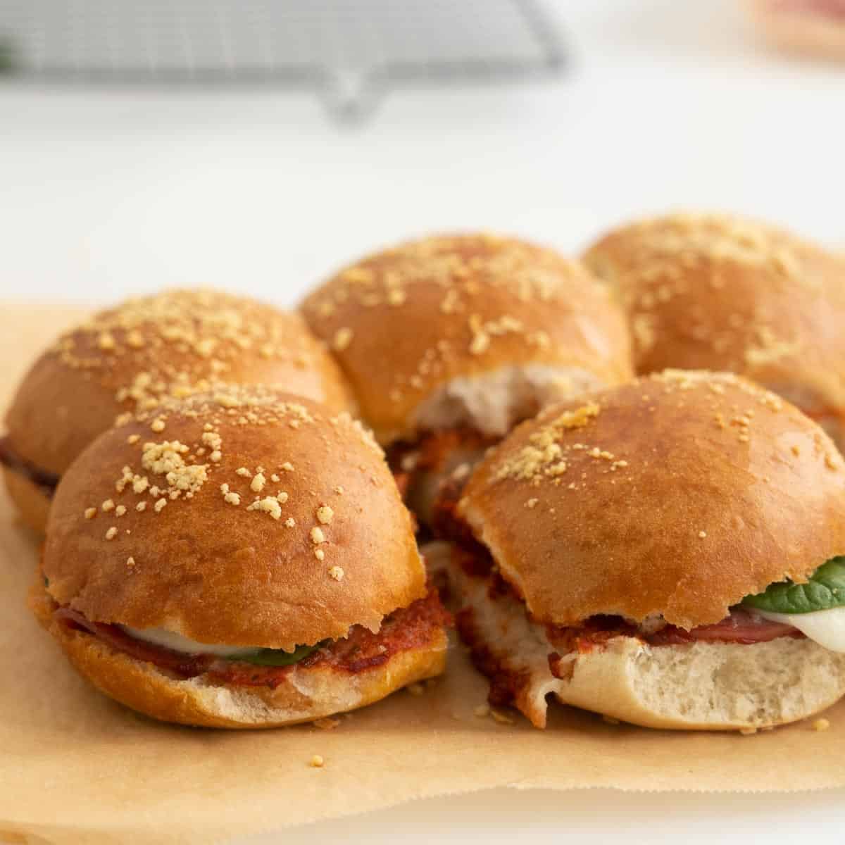 Toasted sliders sitting on a sheet of baking paper.