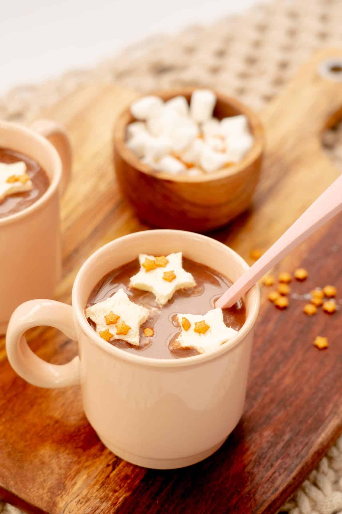 Hot chocolates topped with floating star-shaped hot chocolate toppers and star sprinkles.