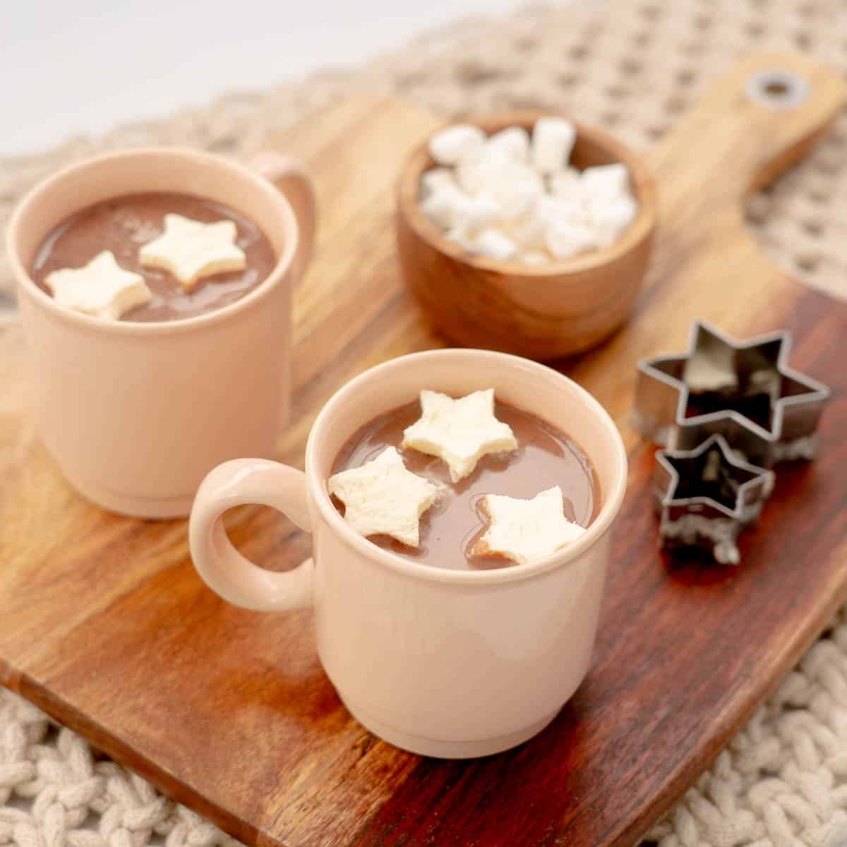 Two mugs of hot chocolate with floating star-shaped  hot chocolate toppers