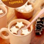 Two mugs of hot chocolate with floating star-shaped hot chocolate toppers with text overlay.