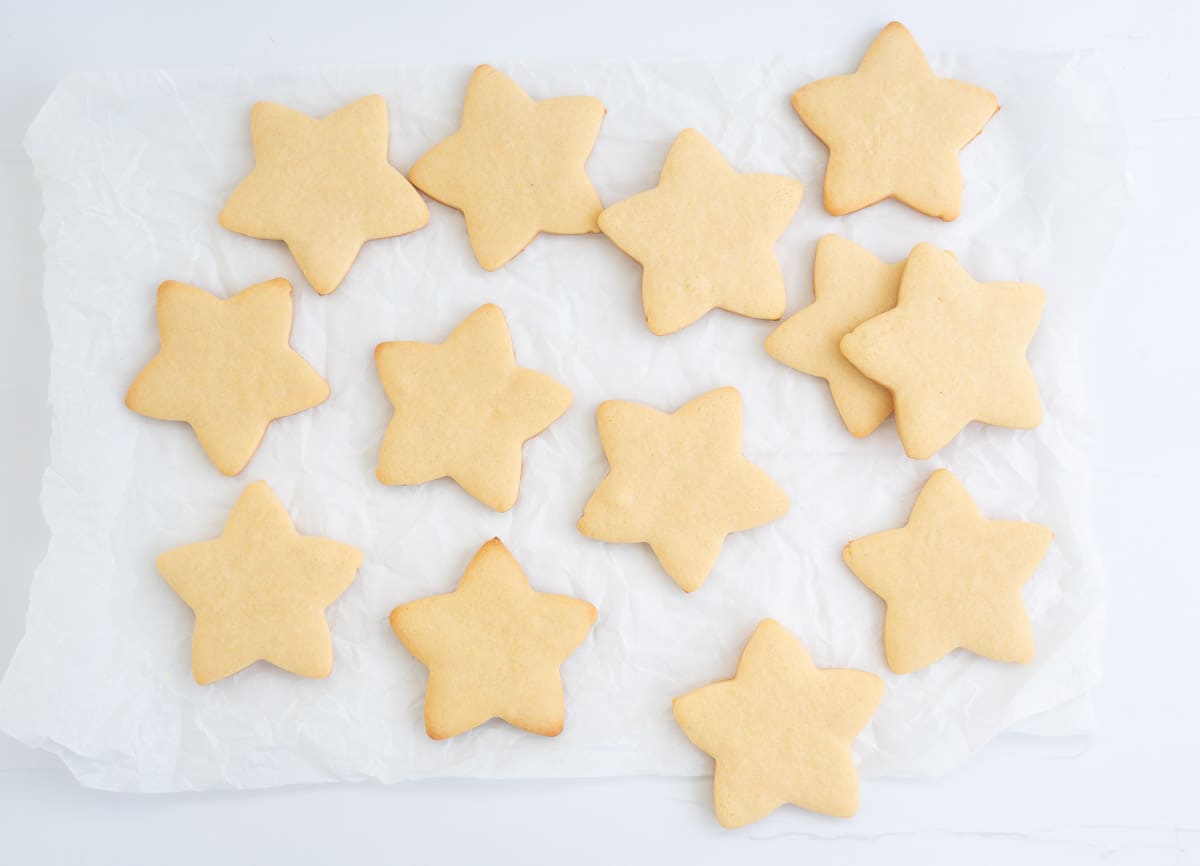 Thirteen star shaped cookies laid out on a piece of crumpled baking paper. 