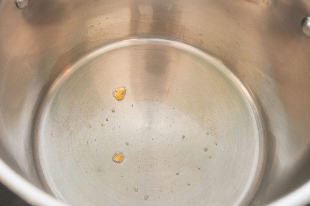 2 popcorn kernels in the bottom of a large oiled saucepan.