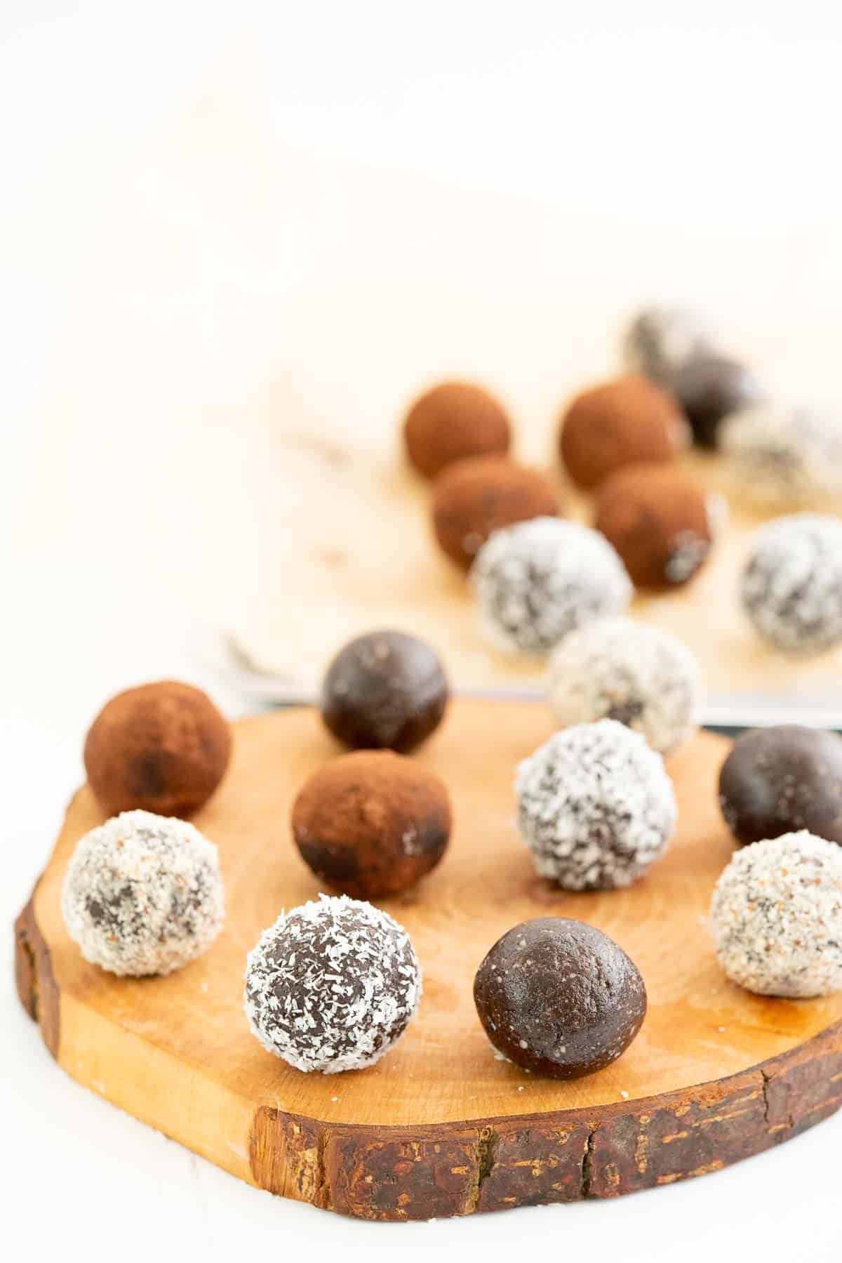A selection of chocolate date balls presented on a rustic  wooden slab.